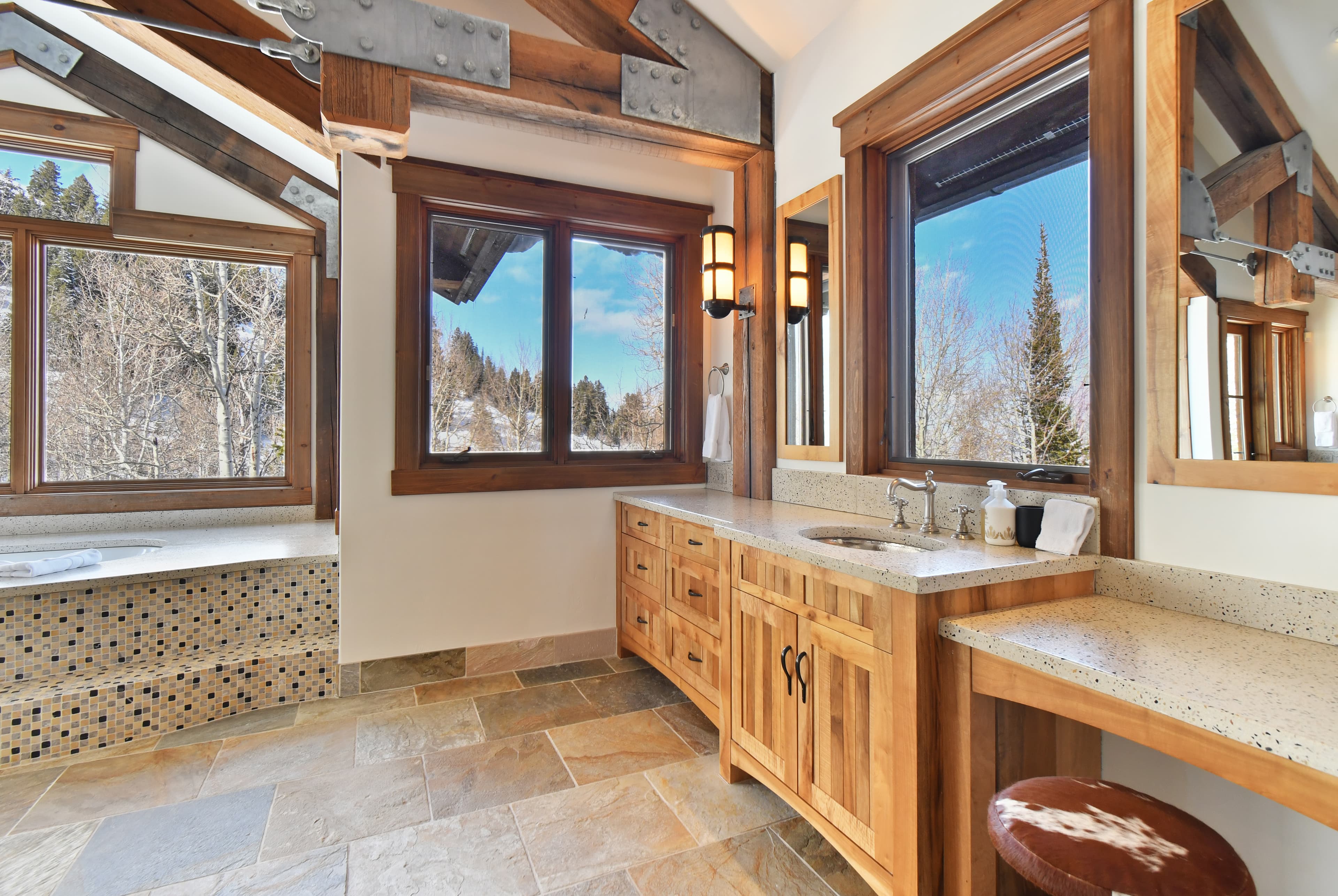 A sink sitting in front of large windows in the en-suite bath, next to the soaking tub.