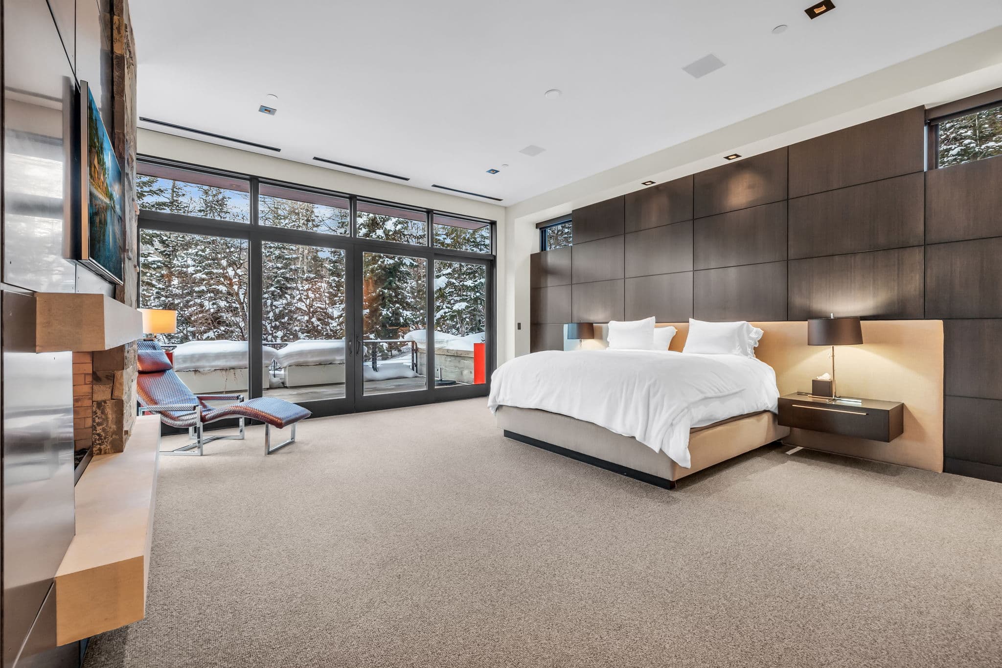 A sleek bedroom with floor-to-ceiling windows and modern decor.