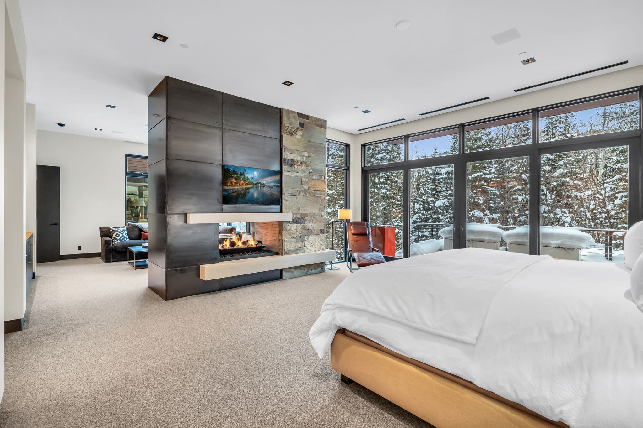 A luxurious bedroom with a fireplace and stunning snowy views.